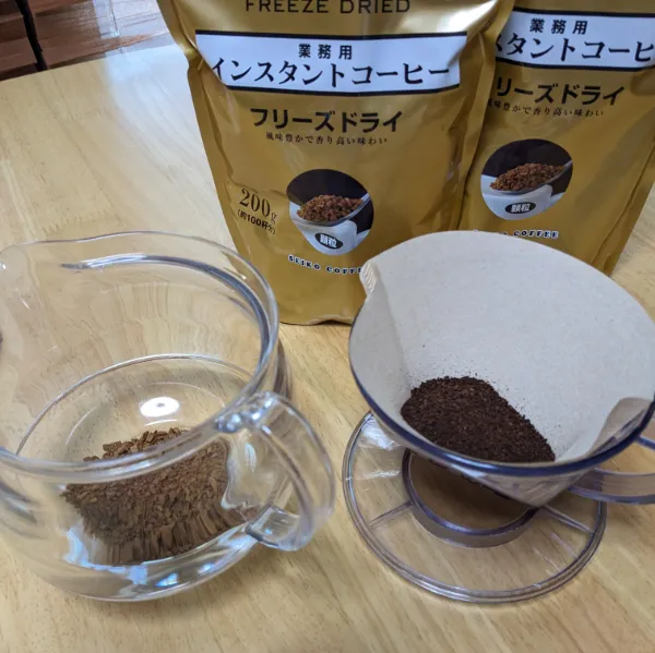 机の上にレギュラーコーヒーの入ったドリッパーとインスタントコーヒーの入ったクリアポットが置かれている様子